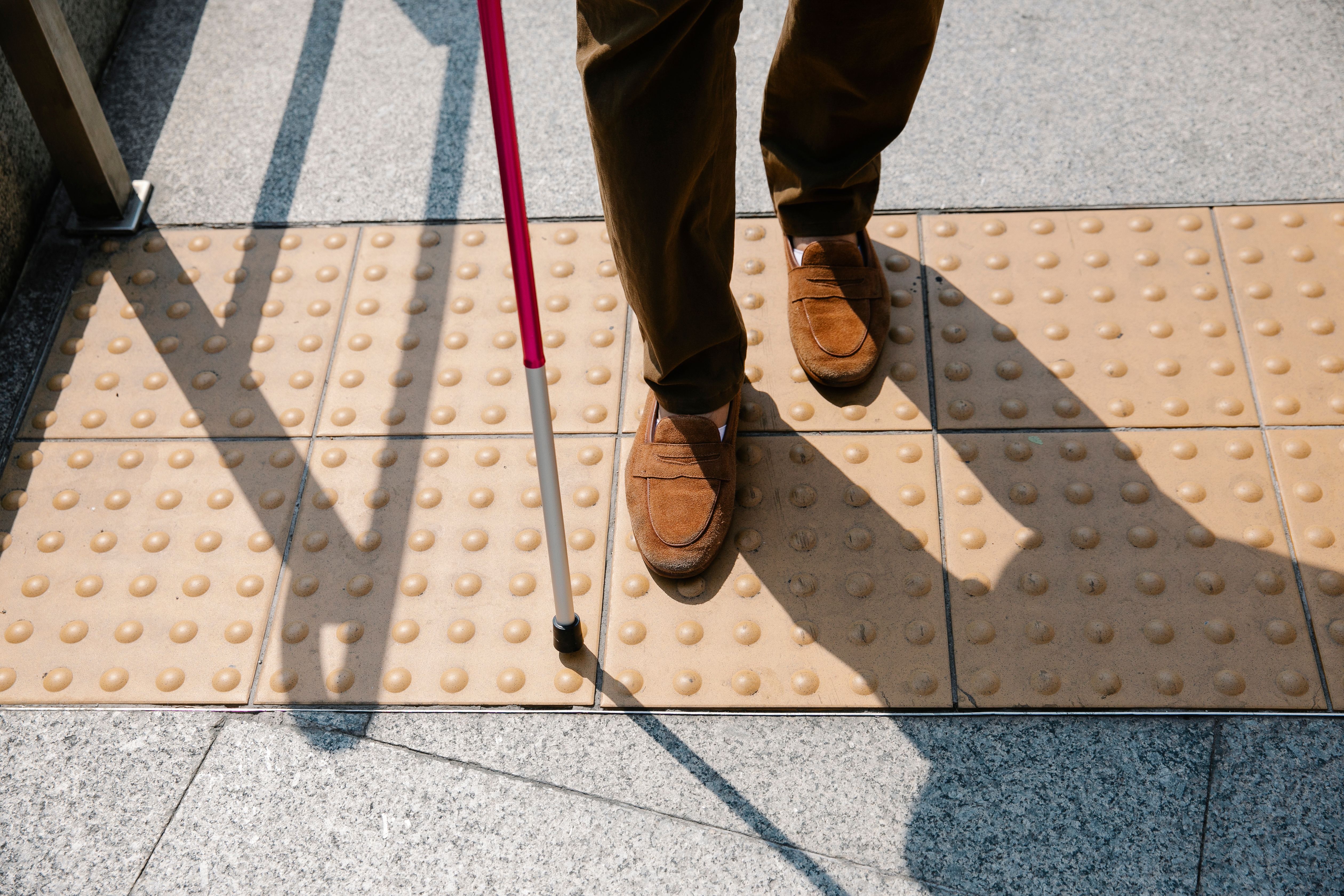 A person using a white cane at a tactile street crossing