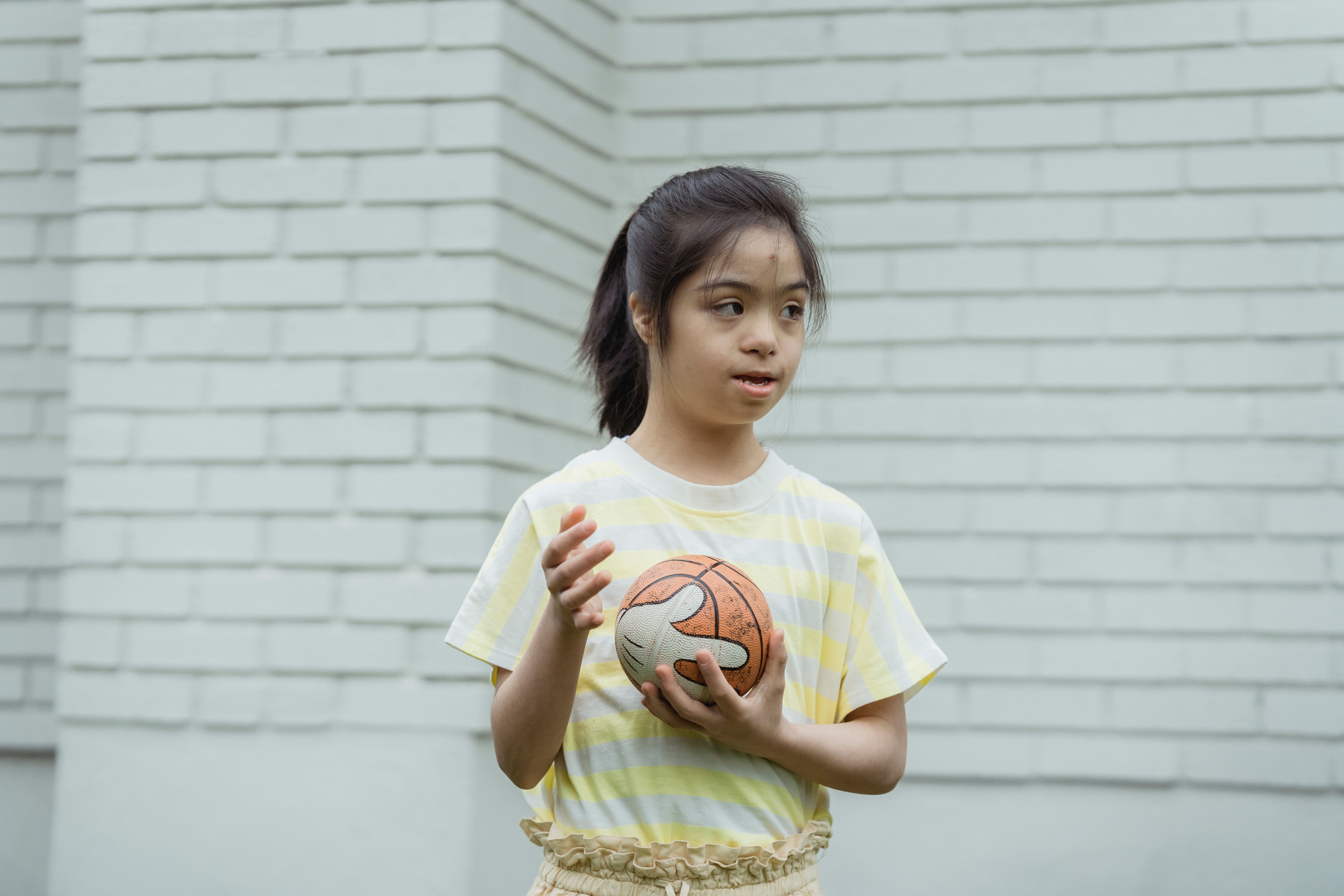 A young woman holding a basketball in an outdoor recreational setting
