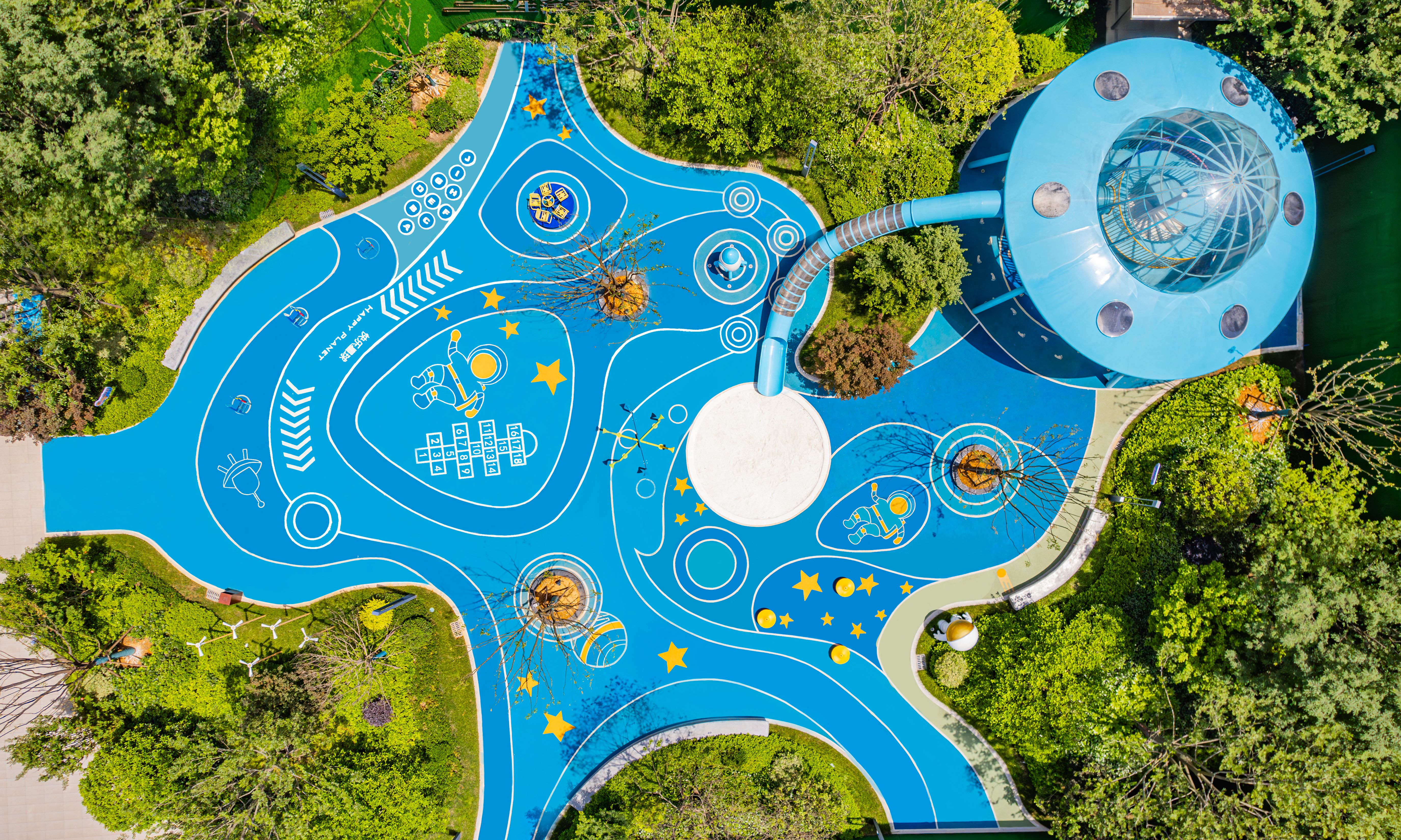 Aerial view of a brightly colored sculptural playground surrounded by trees