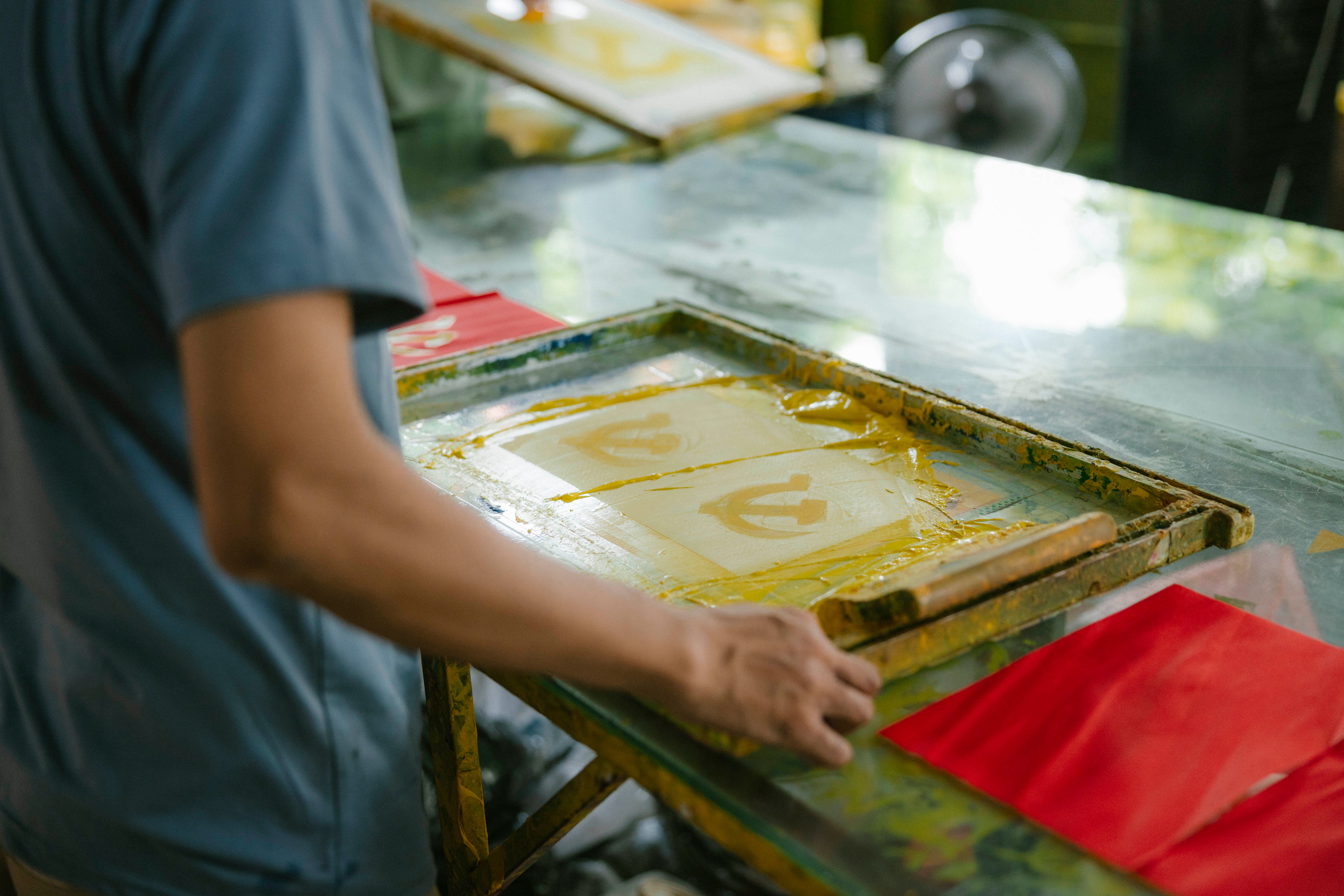 Artist pulling ink across a screen-printing frame