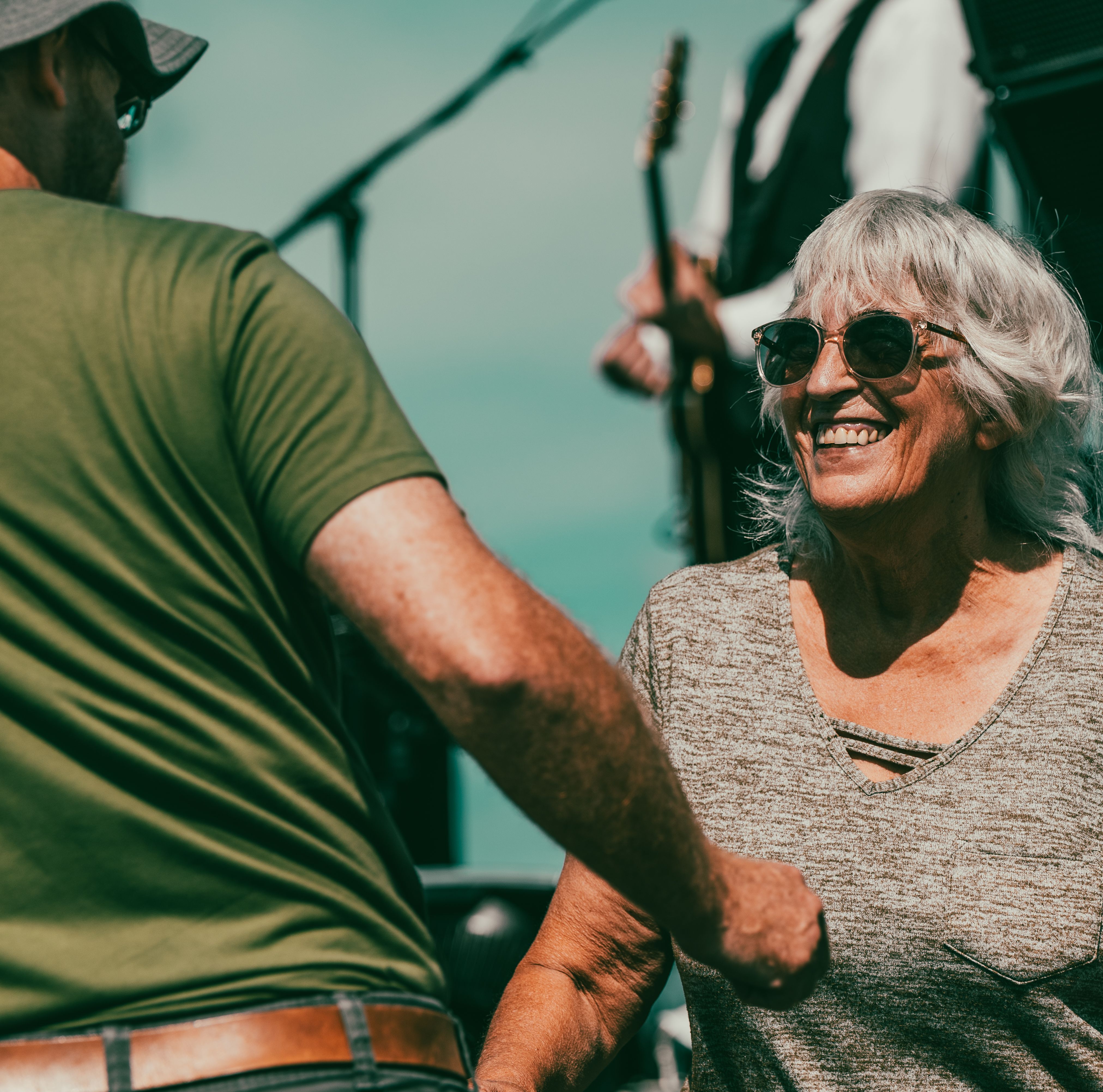 An older woman smiling at an outdoor public gathering