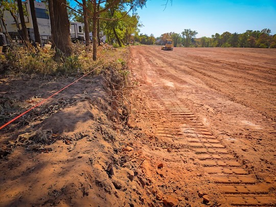 Rough grading and site clearing on Oklahoma red clay with dozer working a cleared field