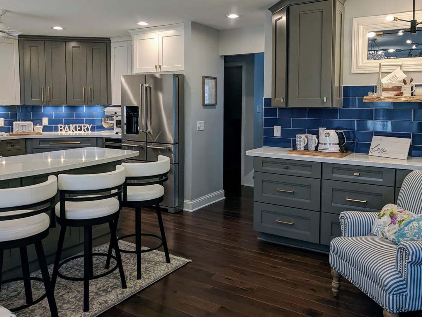 Gray and white shaker kitchen with a blue tile backsplash and quartz island