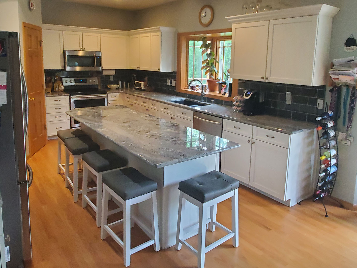 White shaker kitchen with a granite-topped island and dark subway-tile backsplash