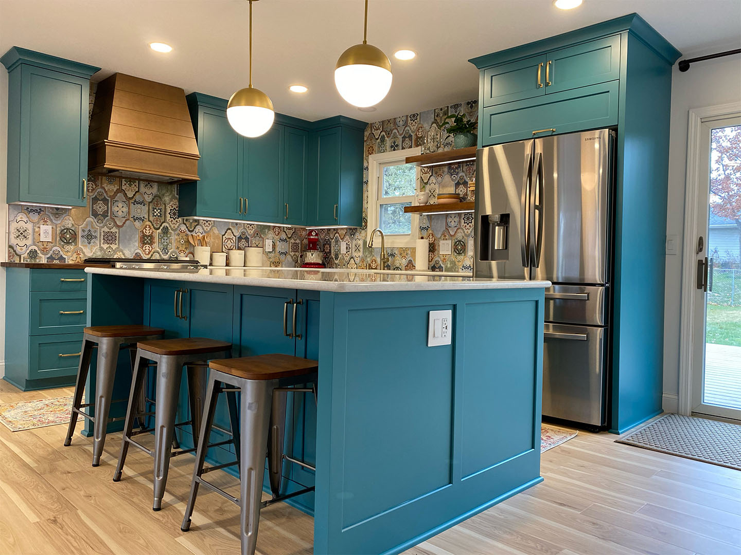 Teal custom kitchen with gold hood by Craftmasters