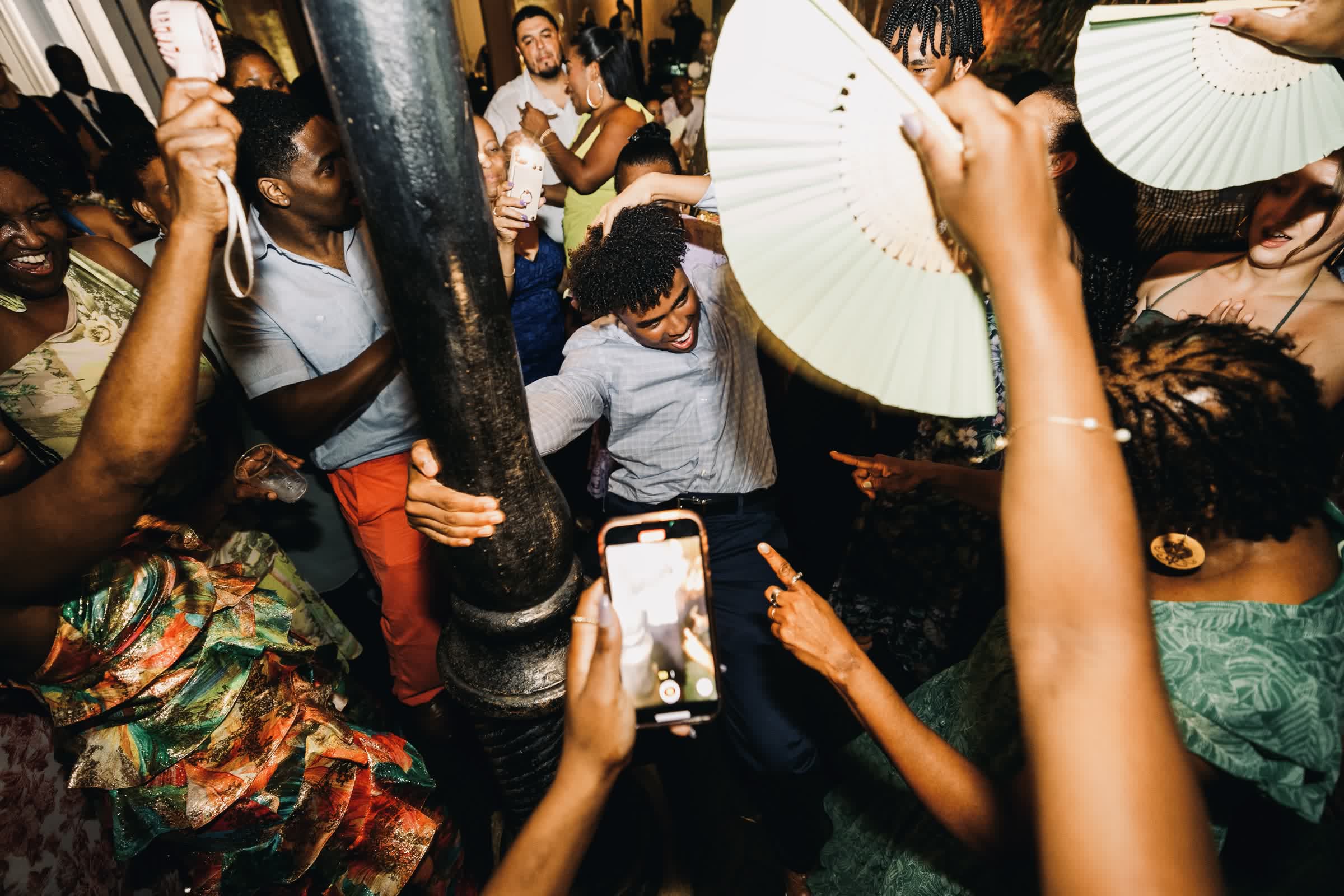 Overhead view of a packed dance floor with guests waving hand fans