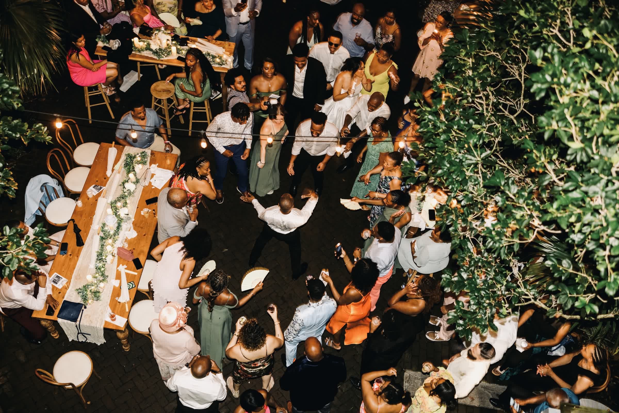 Guests gathered around long banquet tables at an outdoor New Orleans wedding reception