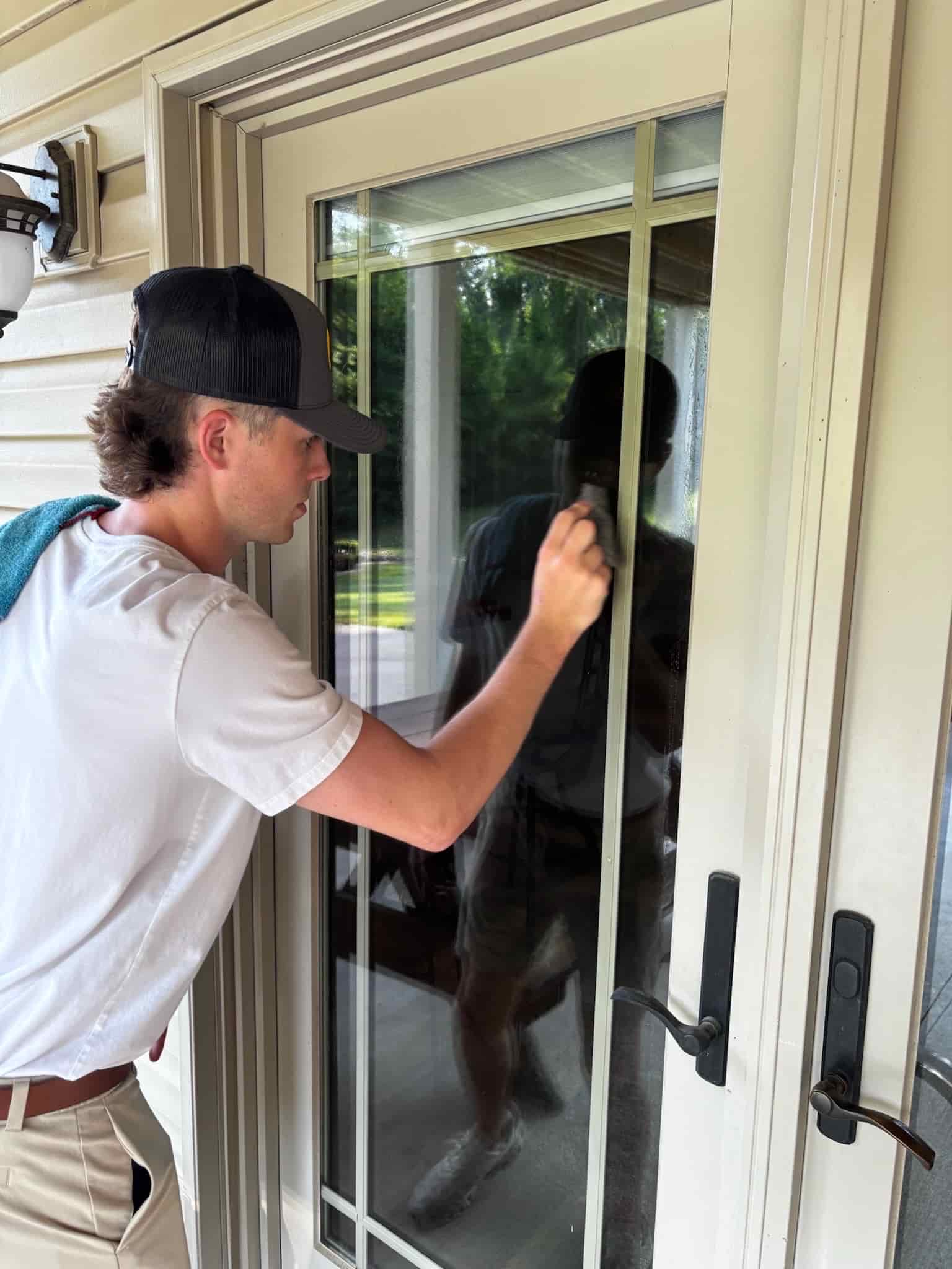 A Bliss Window Washing technician cleaning the exterior windows of a St. Louis home with a water-fed pole