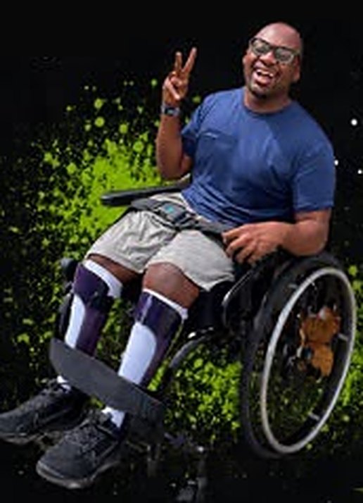 King Nygil smiling and throwing a peace sign from his wheelchair