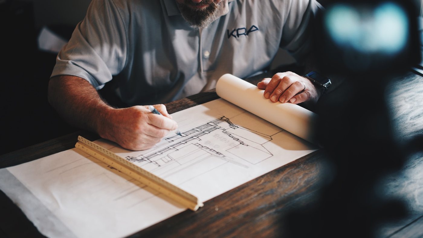 Architect reviewing and marking a building drawing at a desk