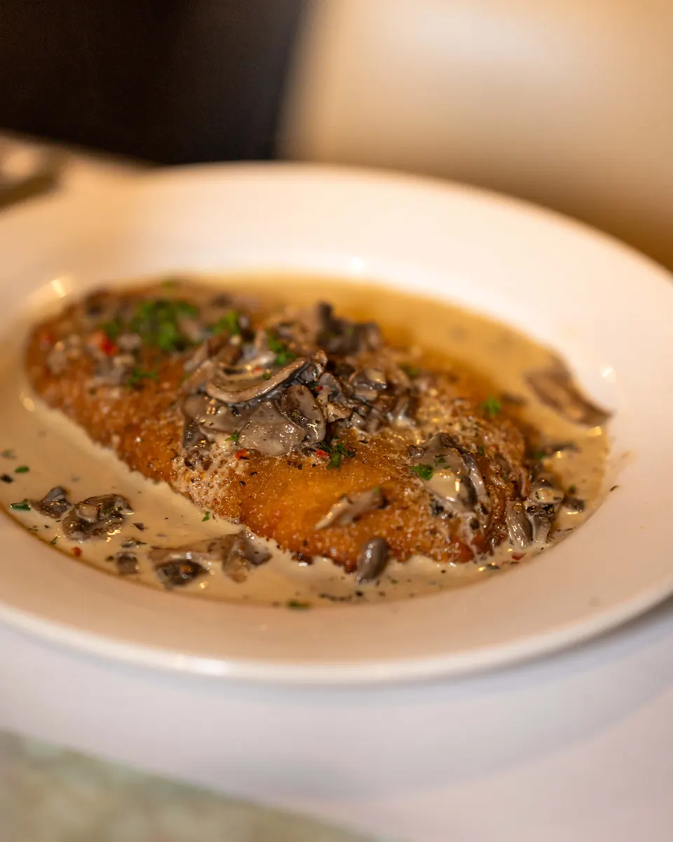 Crumbed chicken cotoletta served with the house funghi sauce