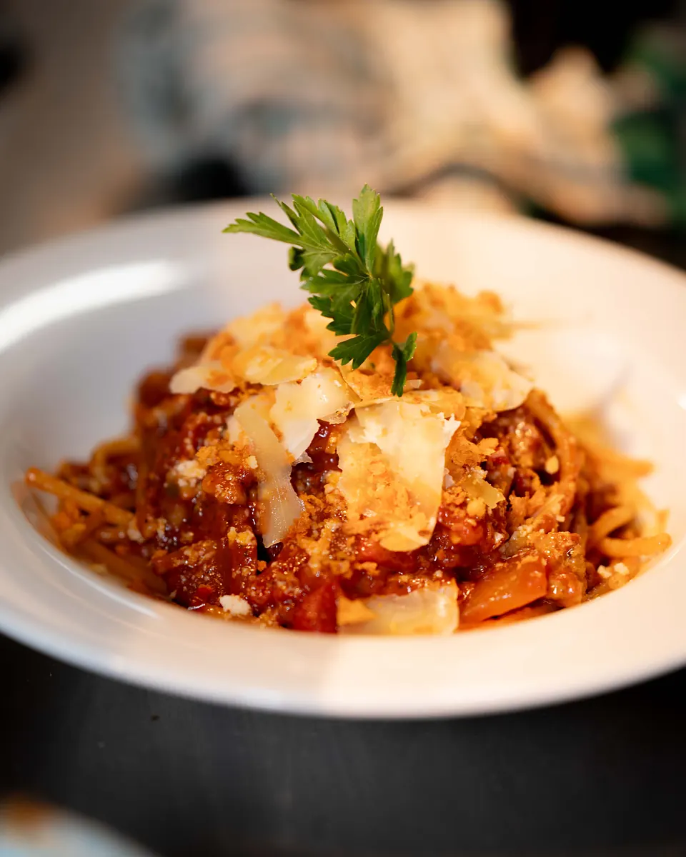 Spaghetti bolognese topped with shaved parmigiano and fresh parsley
