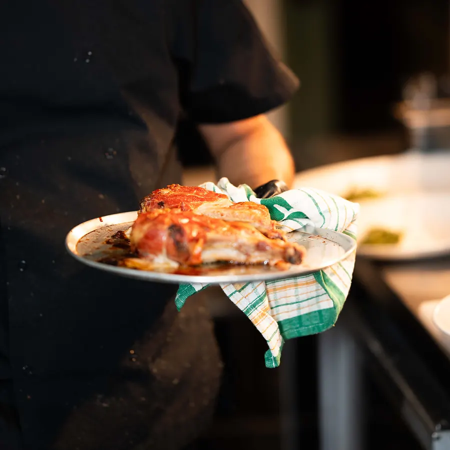 A Grappino chef carrying a plate of the Maiale pork cutlet from the kitchen