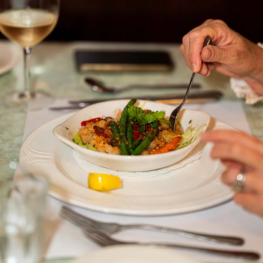 A guest sharing a bowl of garlic prawns and green beans at the table