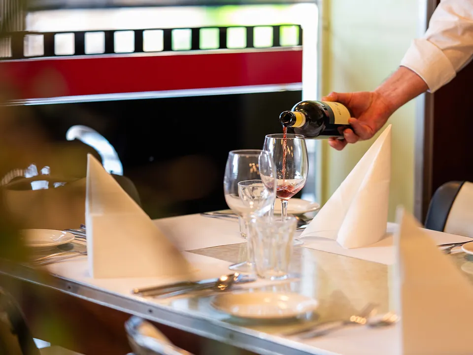 Red wine poured at a beautifully set table by the window at Grappino