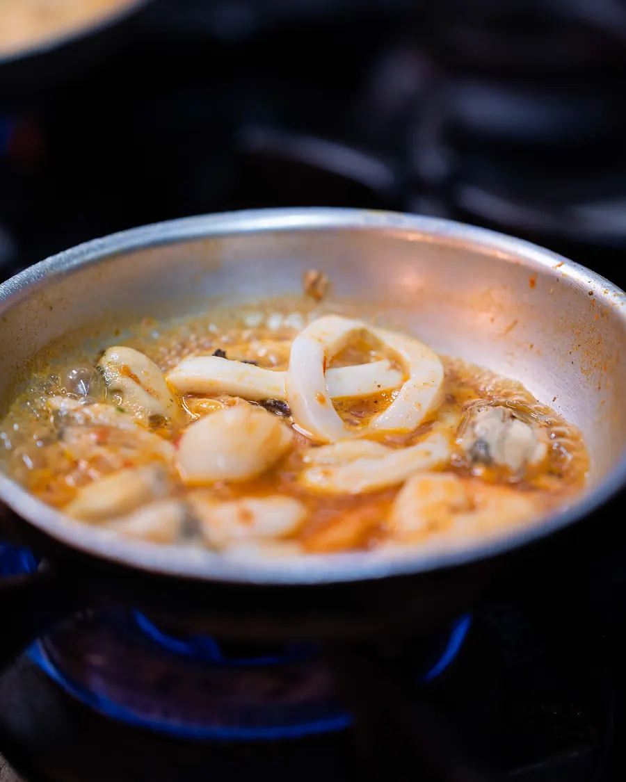 Scallops, calamari, mussels and prawns simmering in the pan for the seafood marinara at Grappino