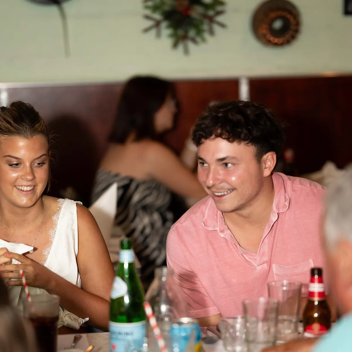 Friends smiling and chatting around a busy table at Grappino