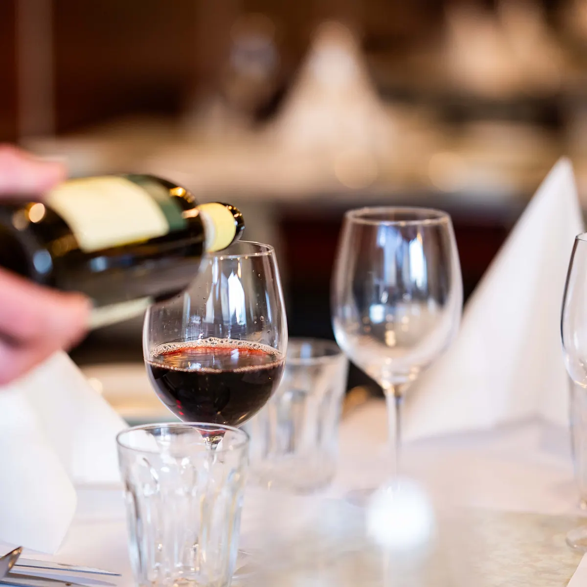 Red wine being poured at a set table in the Grappino dining room