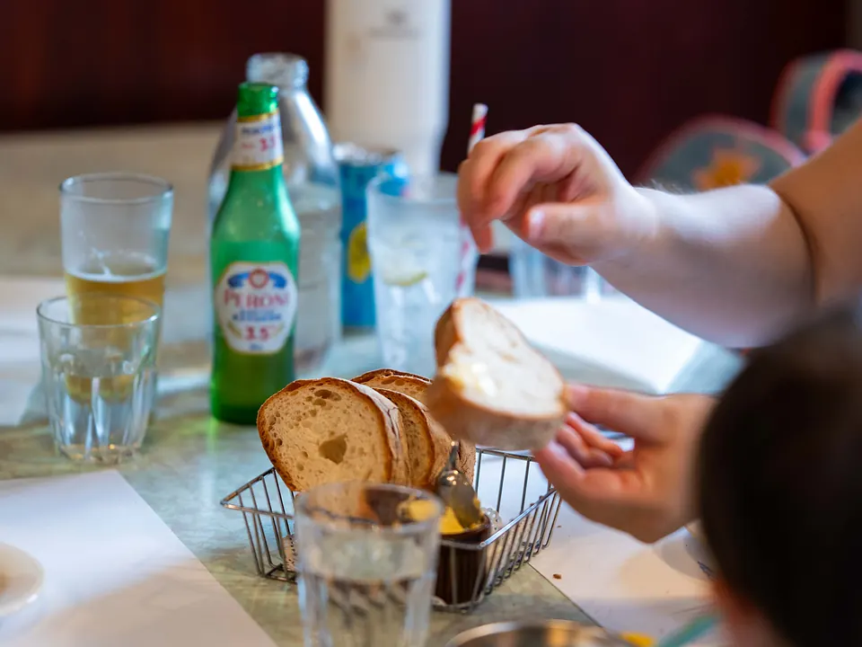 A family passing bread and drinks across a shared table at Grappino
