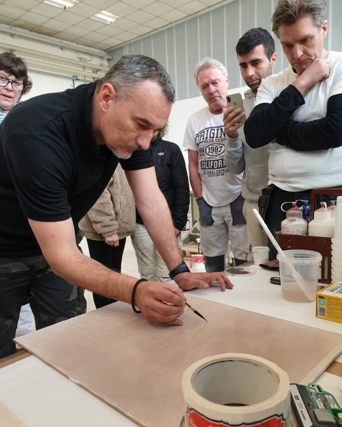 A student burnishing a Venetian plaster wall with guidance during a workshop