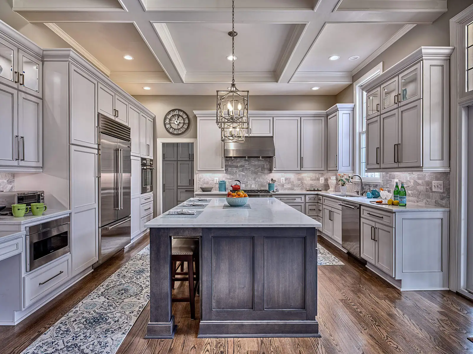 Gray kitchen with coffered ceiling, stone-topped island and stainless steel appliances
