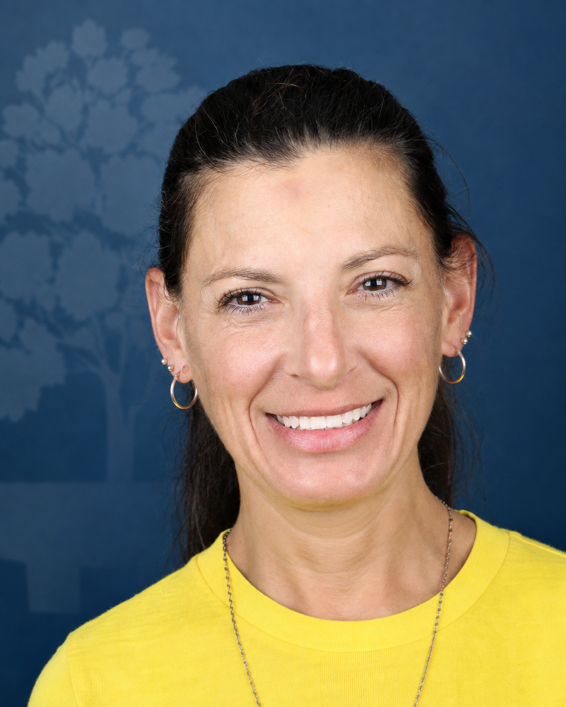 Smiling patient with dark hair and hoop earrings, portrait after dental implant treatment