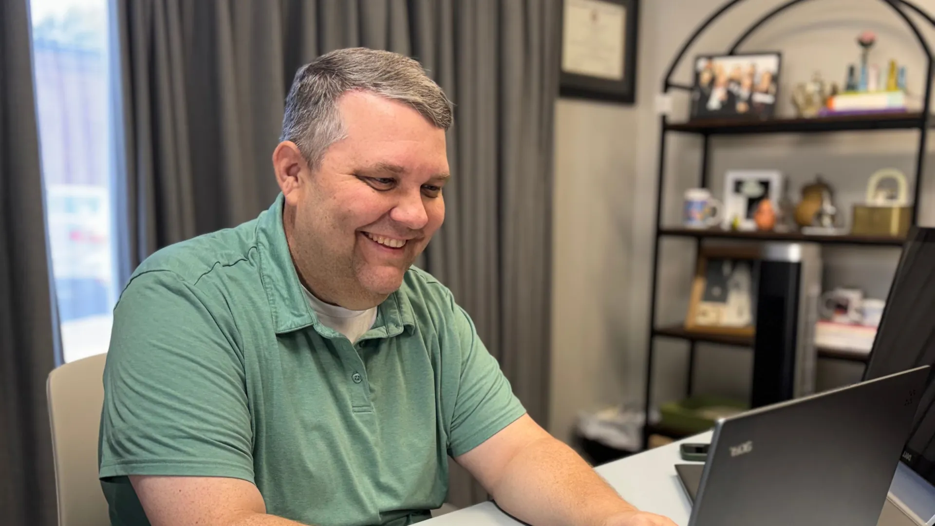 Chip, founder of Ensemble Bookkeeping, smiling while working on a laptop at his desk.