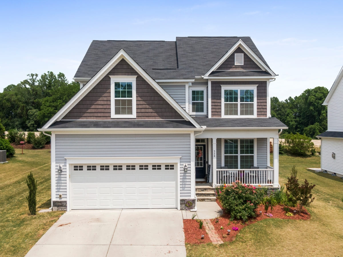 Two-story modern suburban home with gray siding, a spacious driveway, and well-maintained landscaping in front