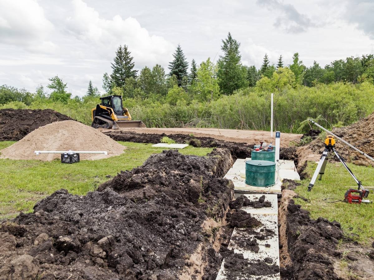 Construction site with excavation work for septic system installation in a grassy area