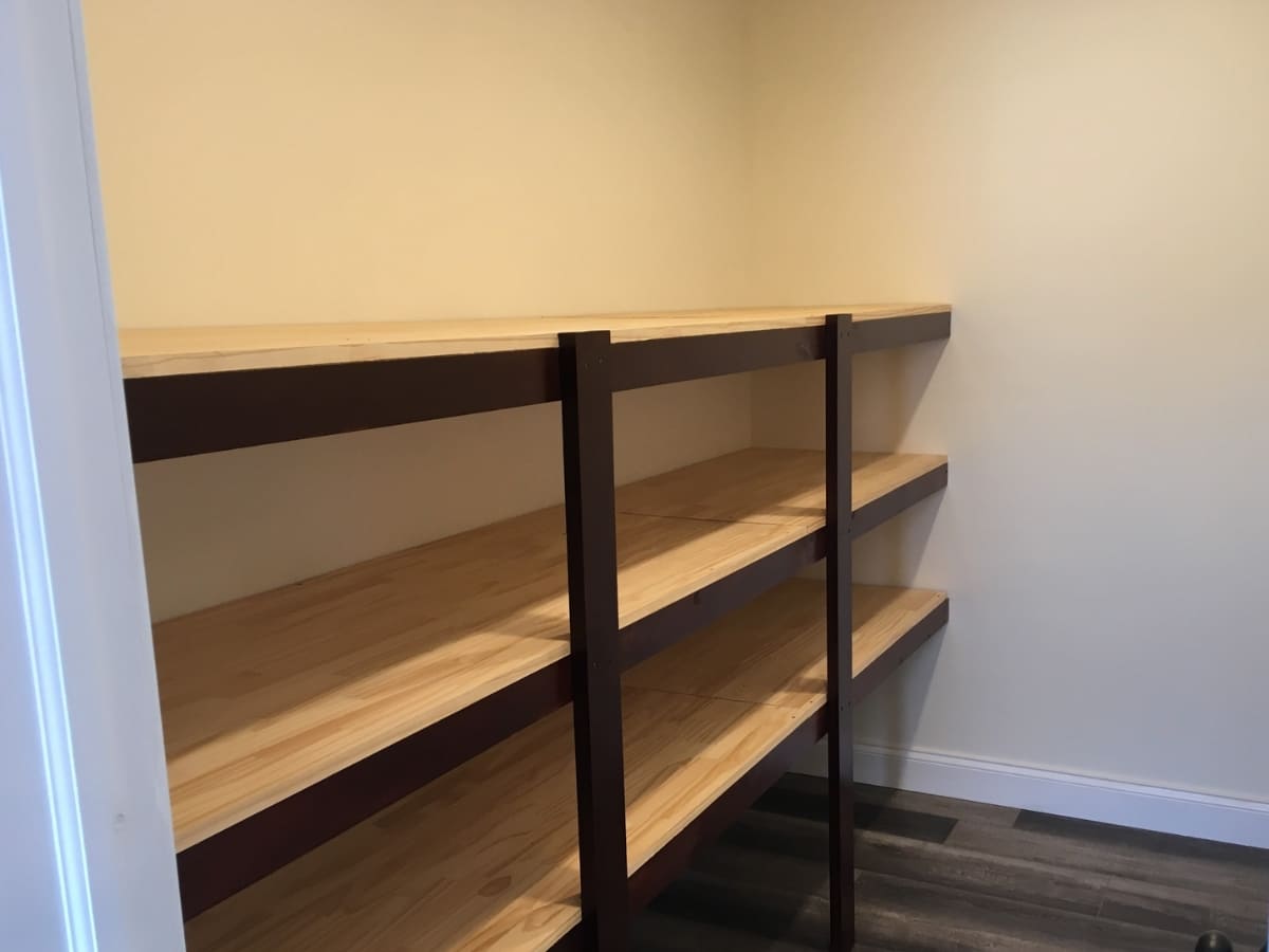 Walk-in closet with custom wooden shelving on a laminate floor.