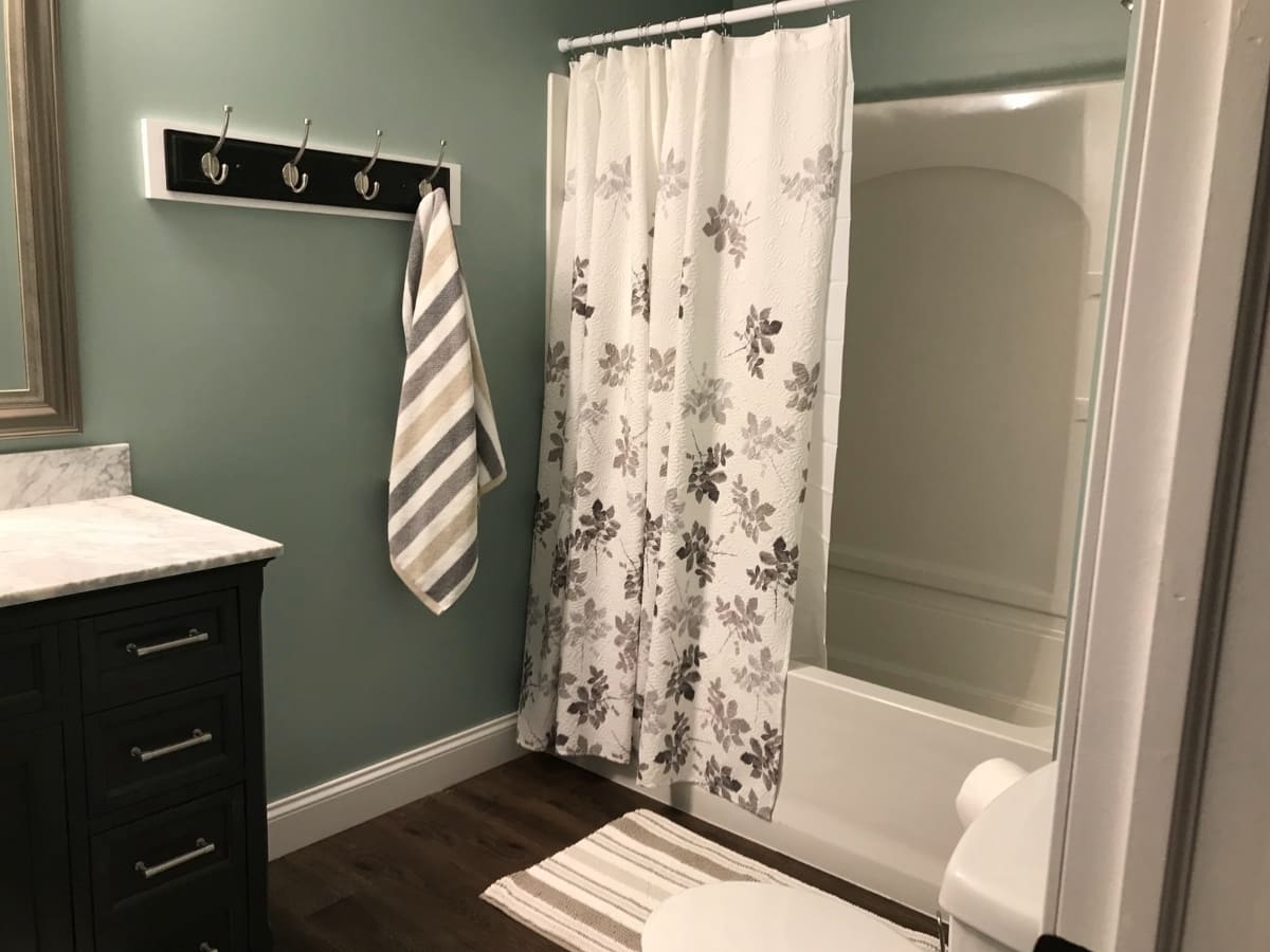 Modern bathroom with a floral shower curtain, dark vanity, and a striped towel hanging on hooks.