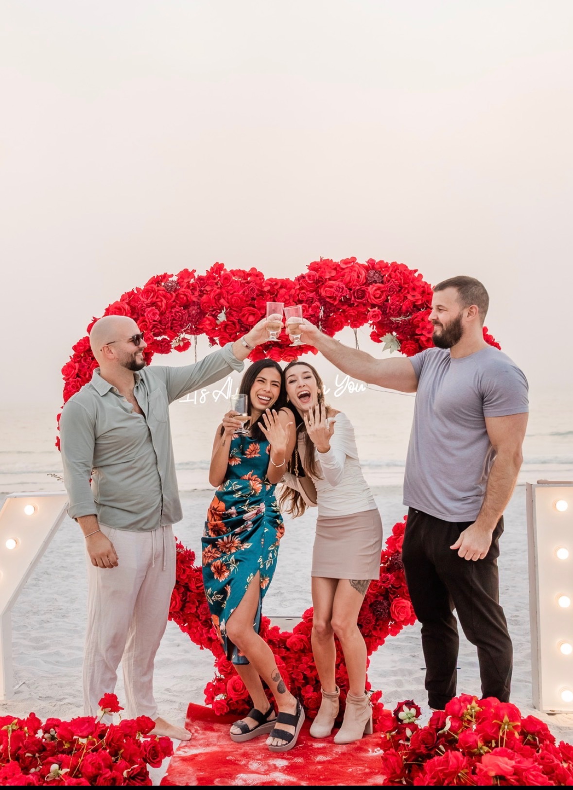 Two brothers, two proposals — Kiley and Cameron with their fiancées under a rose arch on the beach