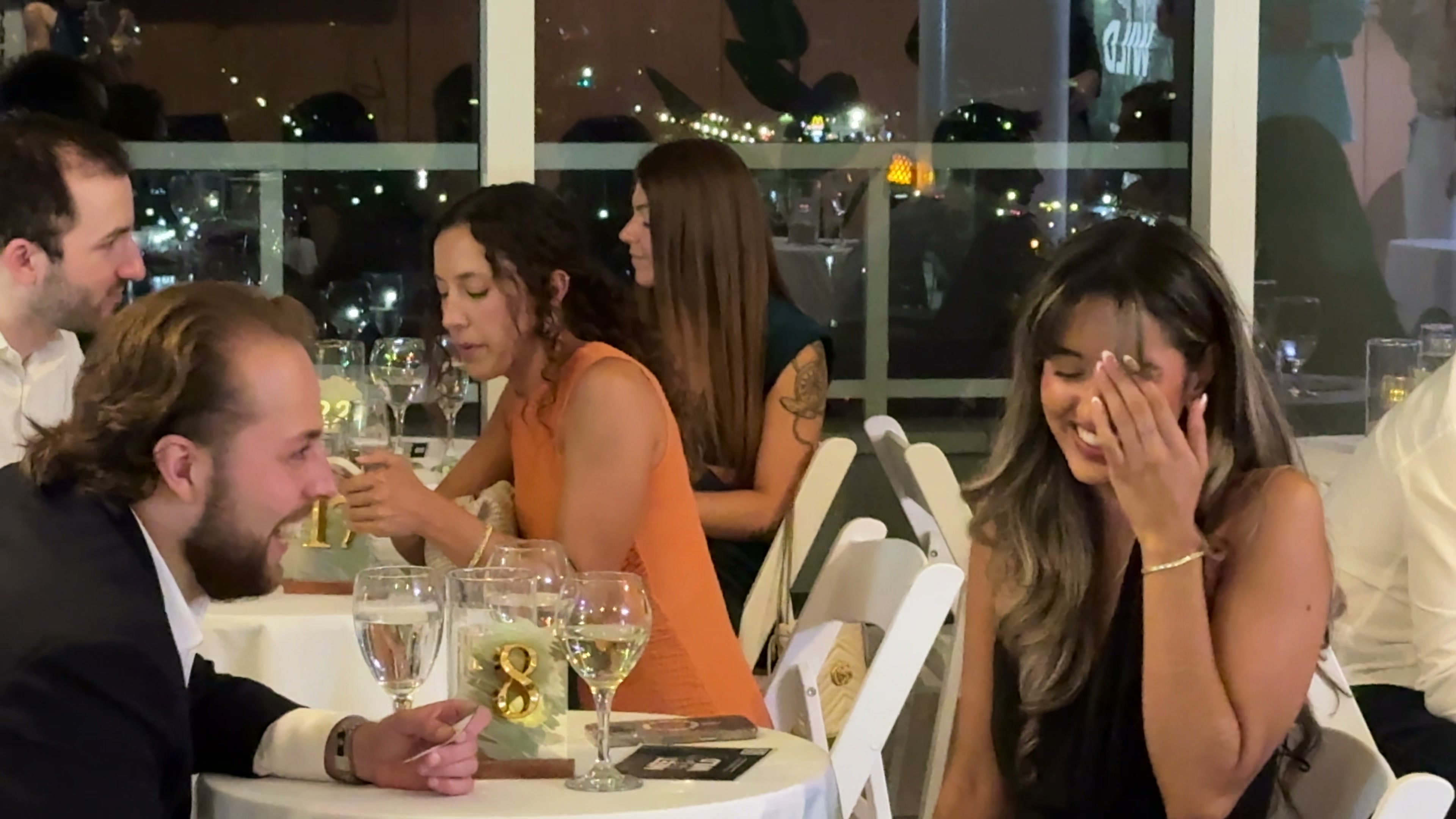 Candid laughter — woman covering face laughing with man smiling at table