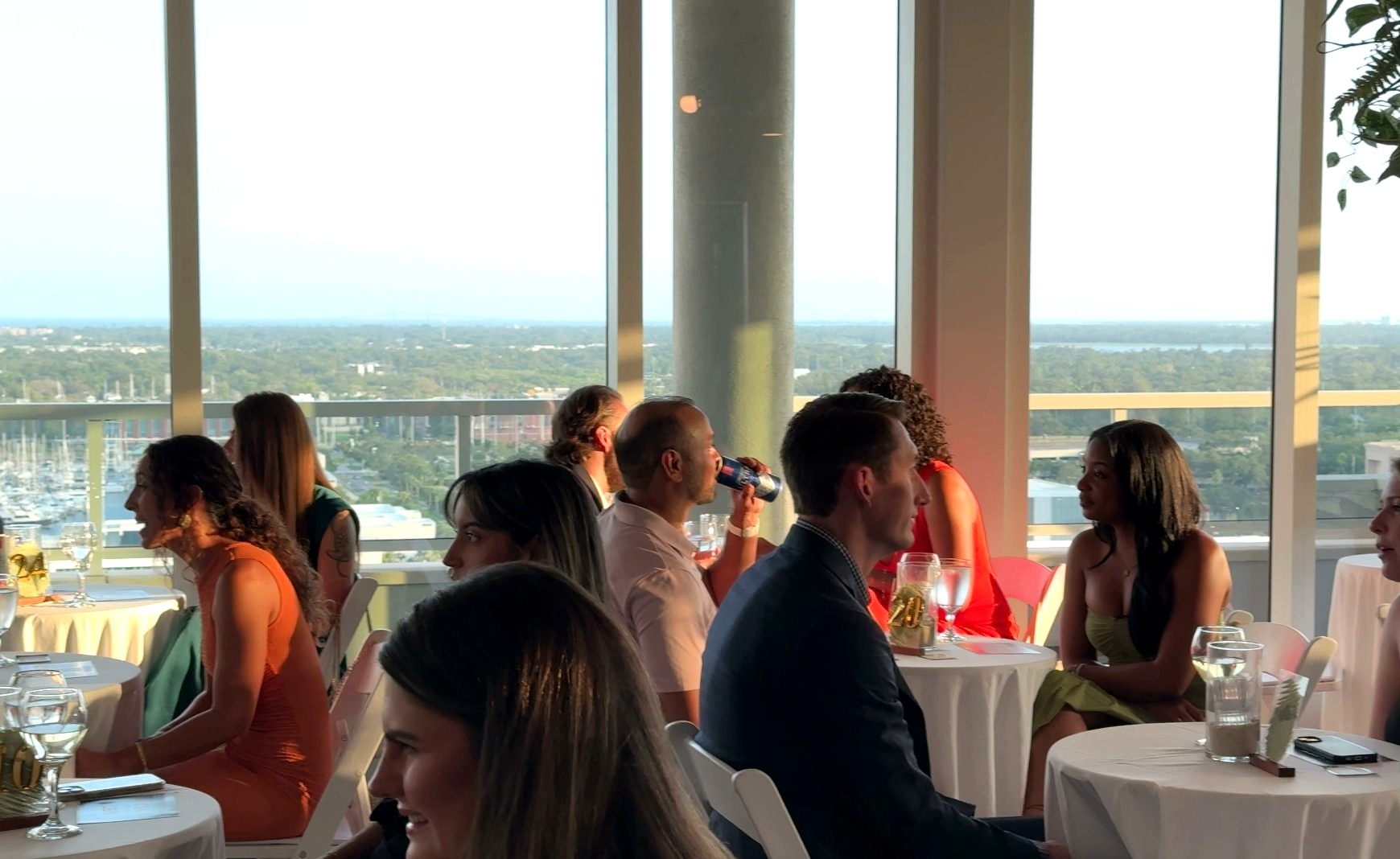 Rooftop city view with couples at tables — marina and skyline visible