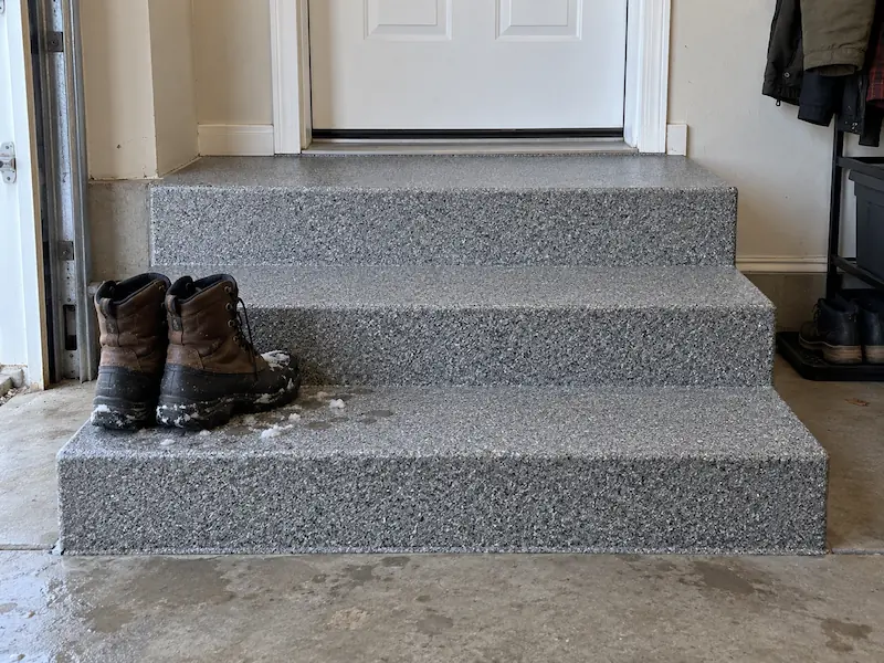 Garage entry steps coated in textured gray quartz epoxy with wet winter boots on the bottom step
