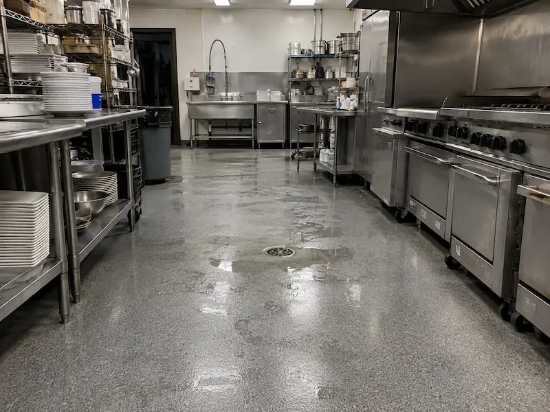 Commercial restaurant kitchen with a seamless gray coated floor, wet around the floor drain