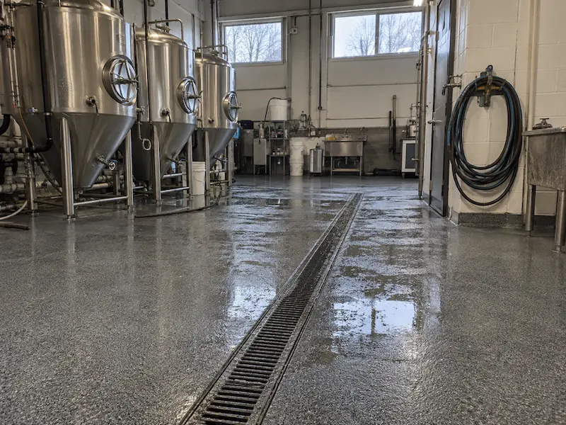 Small brewery production floor with fermentation tanks, a trench drain and a wet coated floor