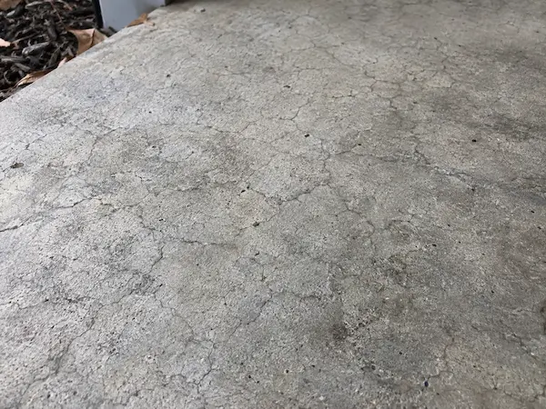 Fine web of shallow map cracking, also called crazing, on a concrete patio surface