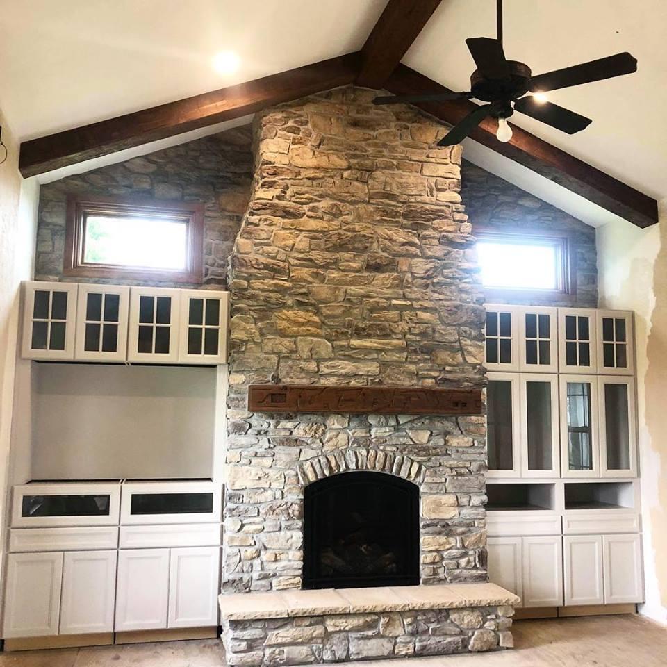 Custom wood-burning fireplace with stone surround installed by Wiegmann Woodworking