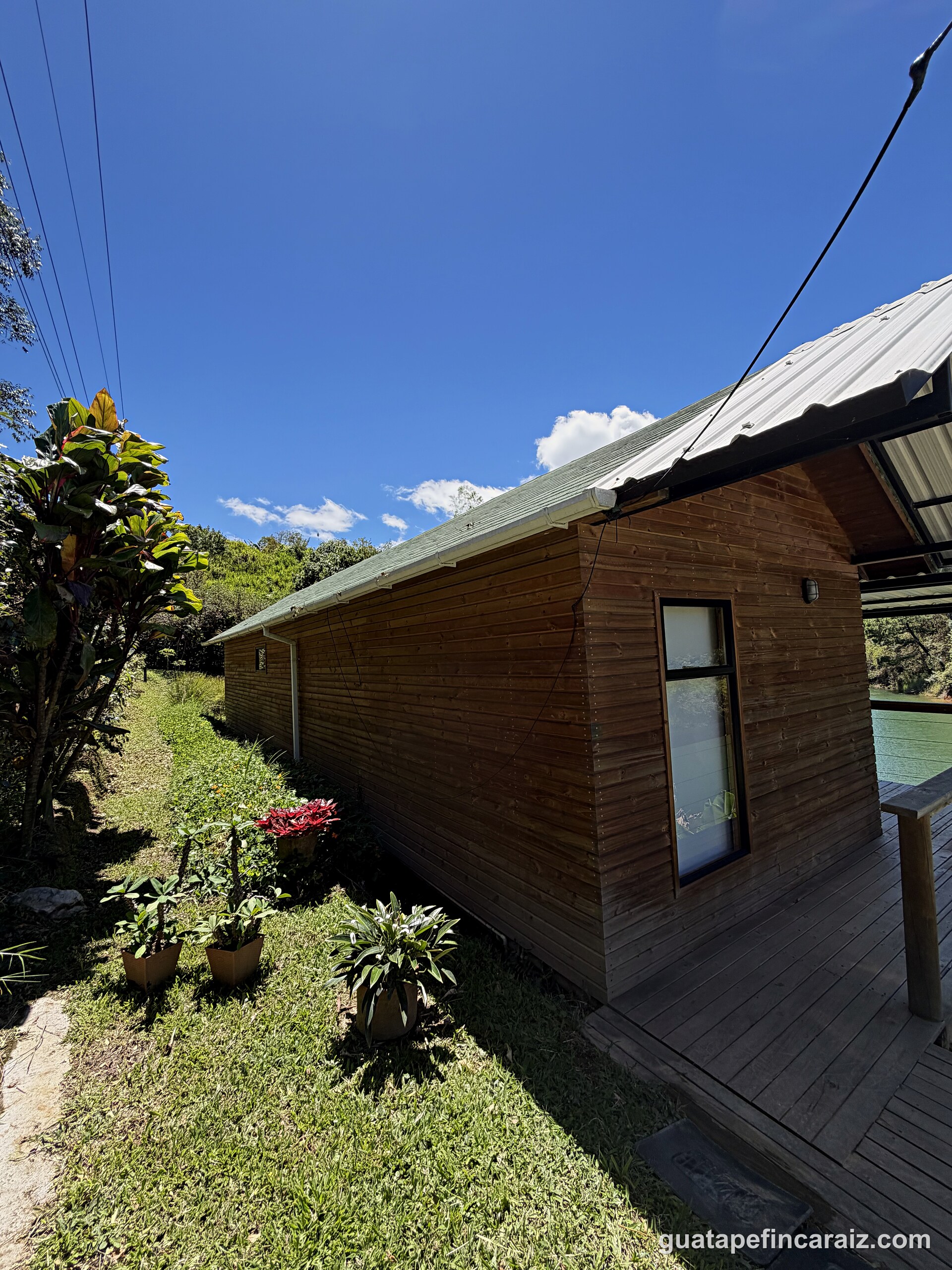 Wood-and-glass cabin exterior along the elevated walkway toward the water at Cabaña del Embalse