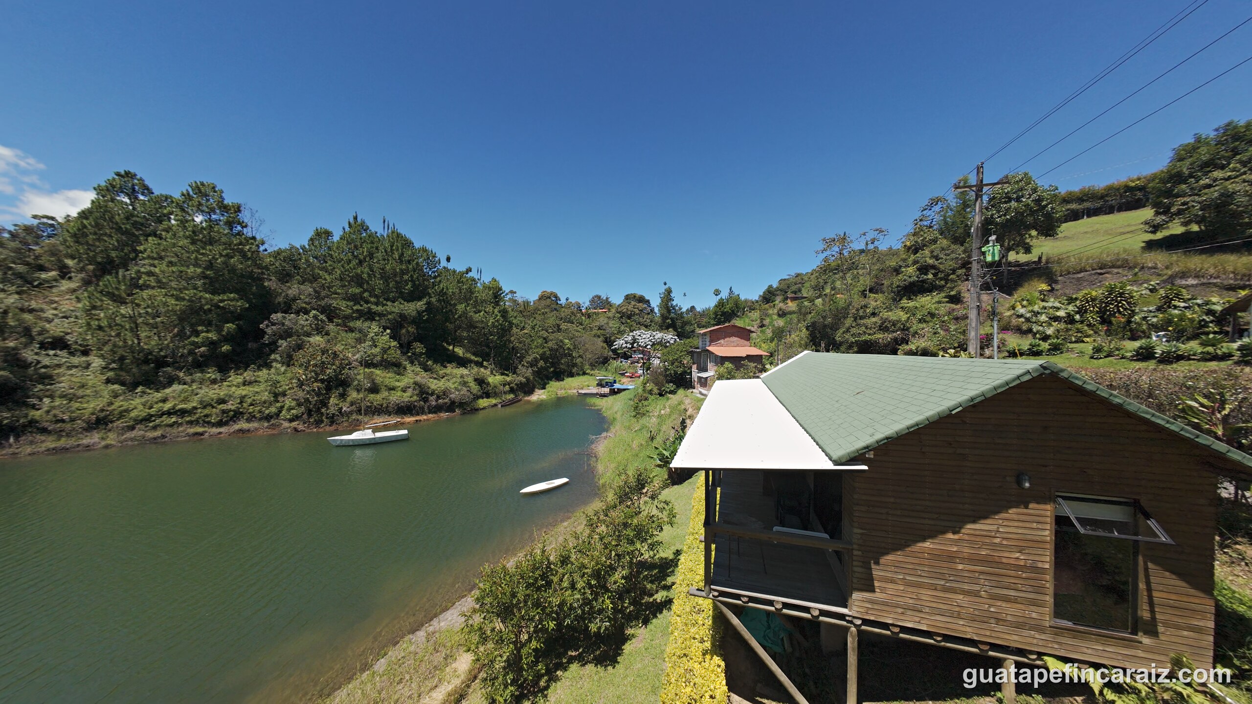 Aerial view of the reservoir inlet at Cabaña del Embalse with moored boats and the cabin roofline on the shoreline
