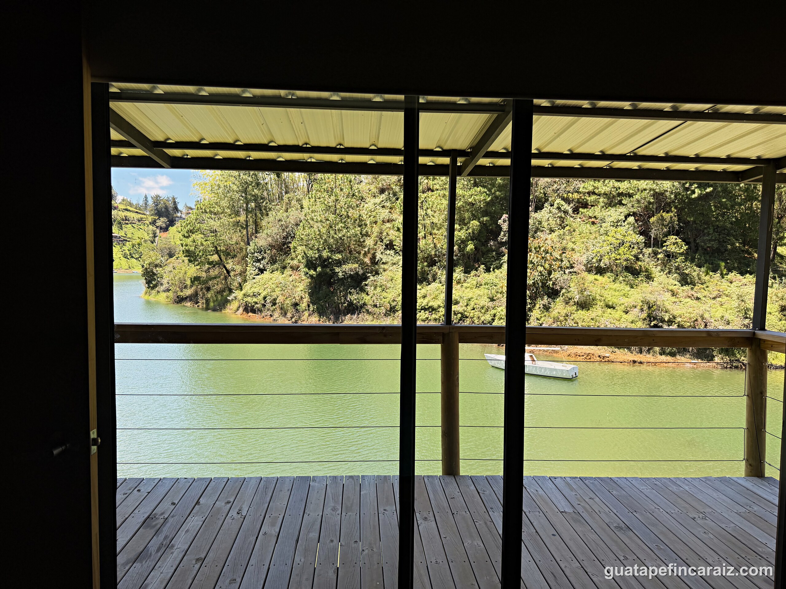 View from inside Cabaña del Embalse through the sliding glass doors to the covered deck and reservoir