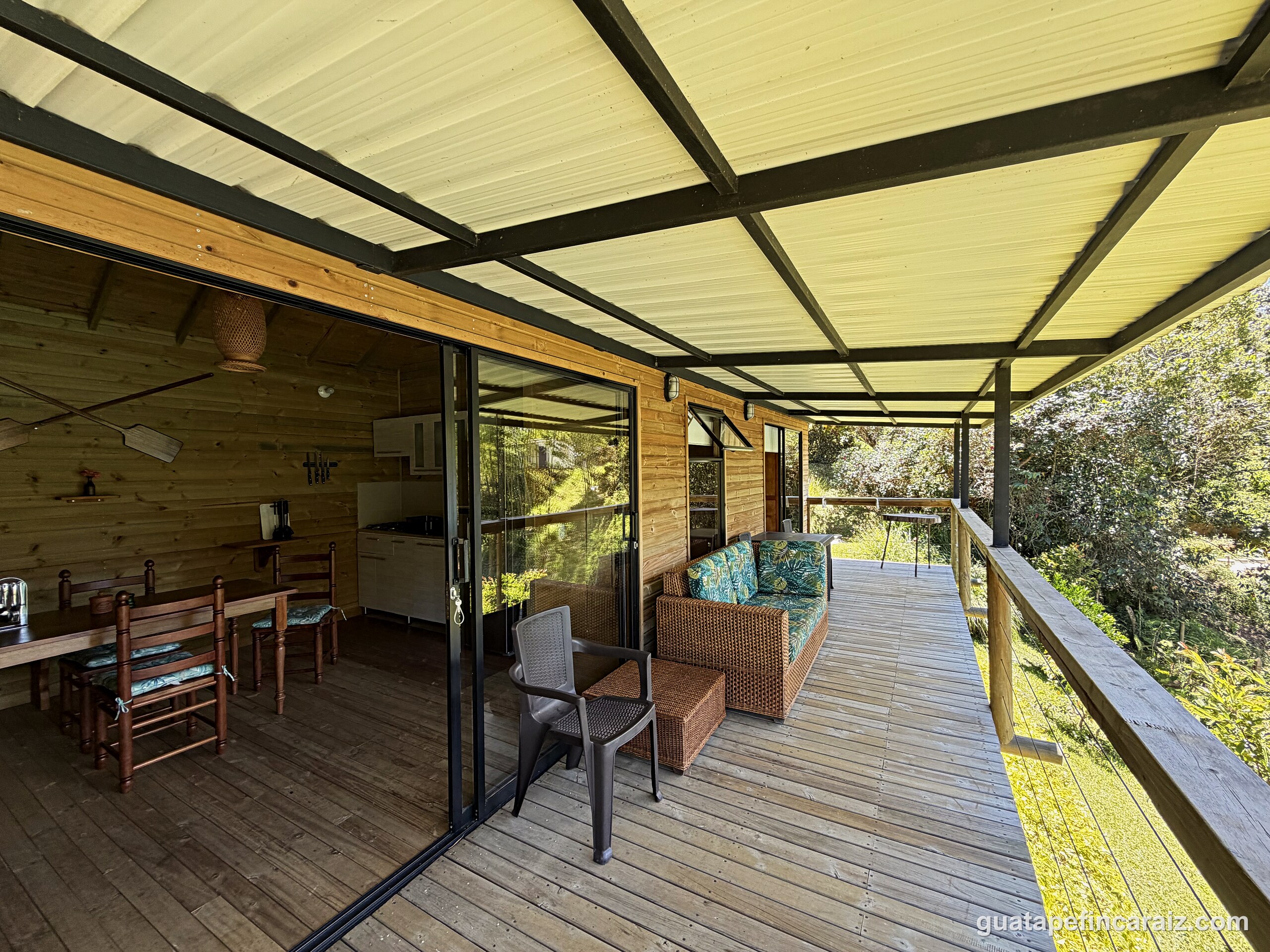 Covered deck at Cabaña del Embalse with outdoor dining table, kitchenette, and lounge seating over the water