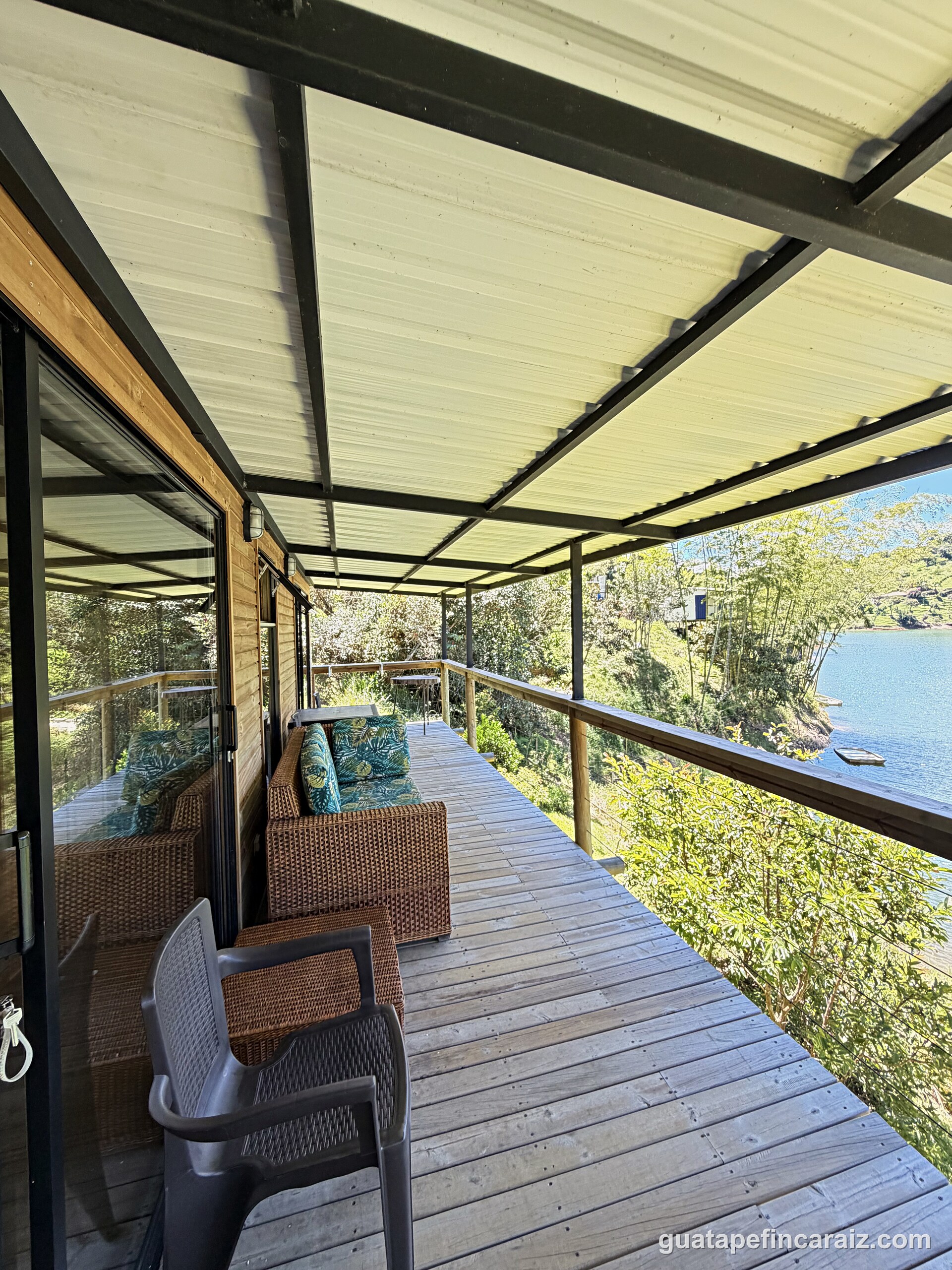 Covered deck walkway at Cabaña del Embalse with wicker lounge seating overlooking the reservoir