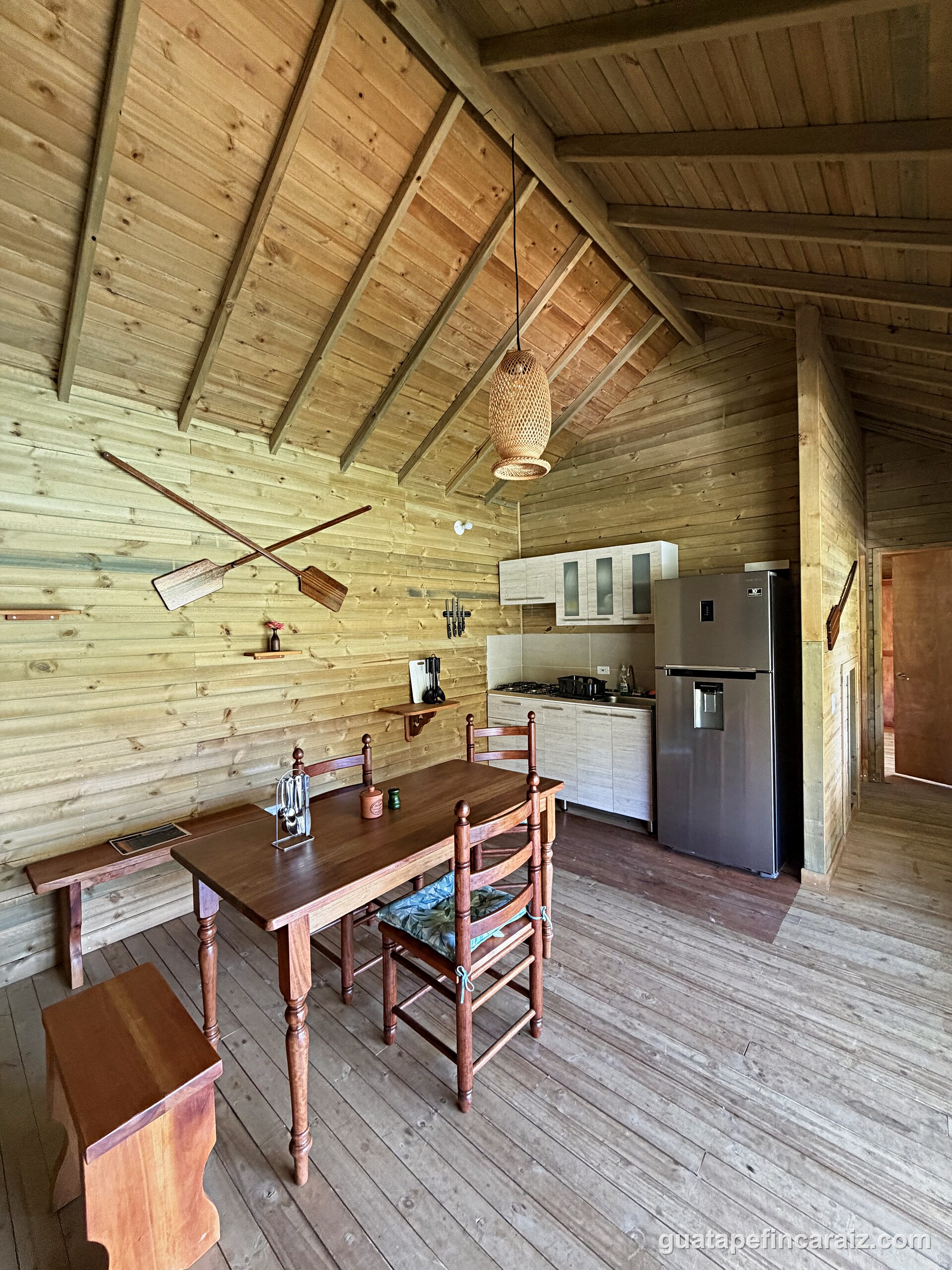Dining table and kitchenette at Cabaña del Embalse with wood-beam ceilings and a wall-mounted TV