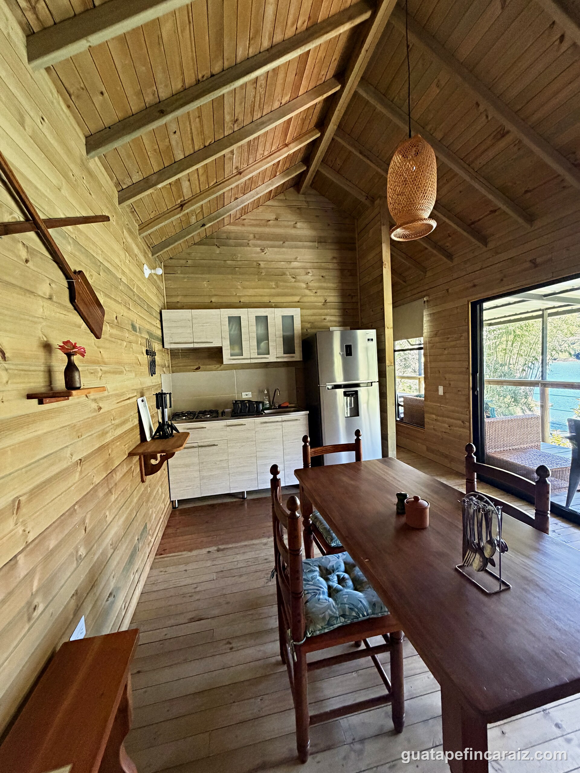 Kitchen and dining area at Cabaña del Embalse with a full-size refrigerator and hallway to the bedrooms