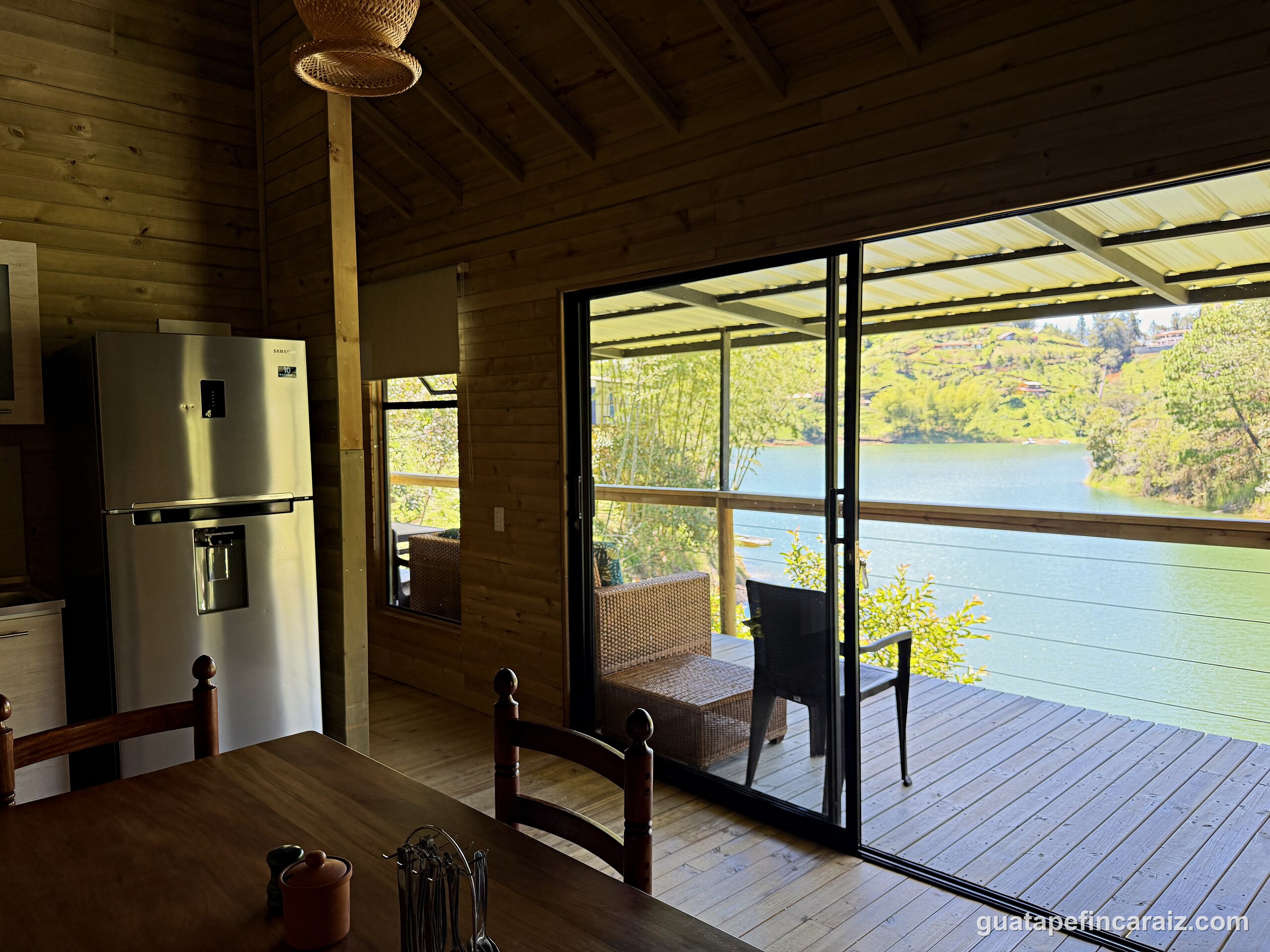 Dining area at Cabaña del Embalse opening through sliding glass doors to the covered deck and reservoir view