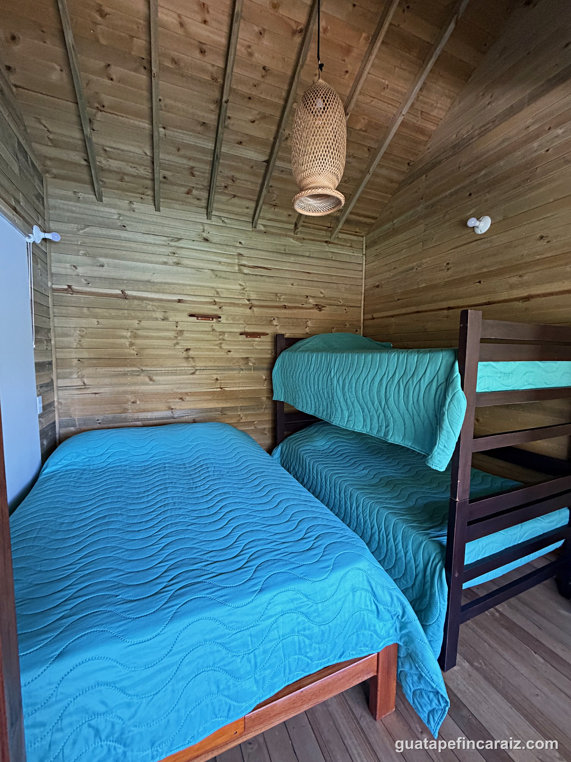 Second bedroom at Cabaña del Embalse with a double bed and bunk bed in turquoise linens