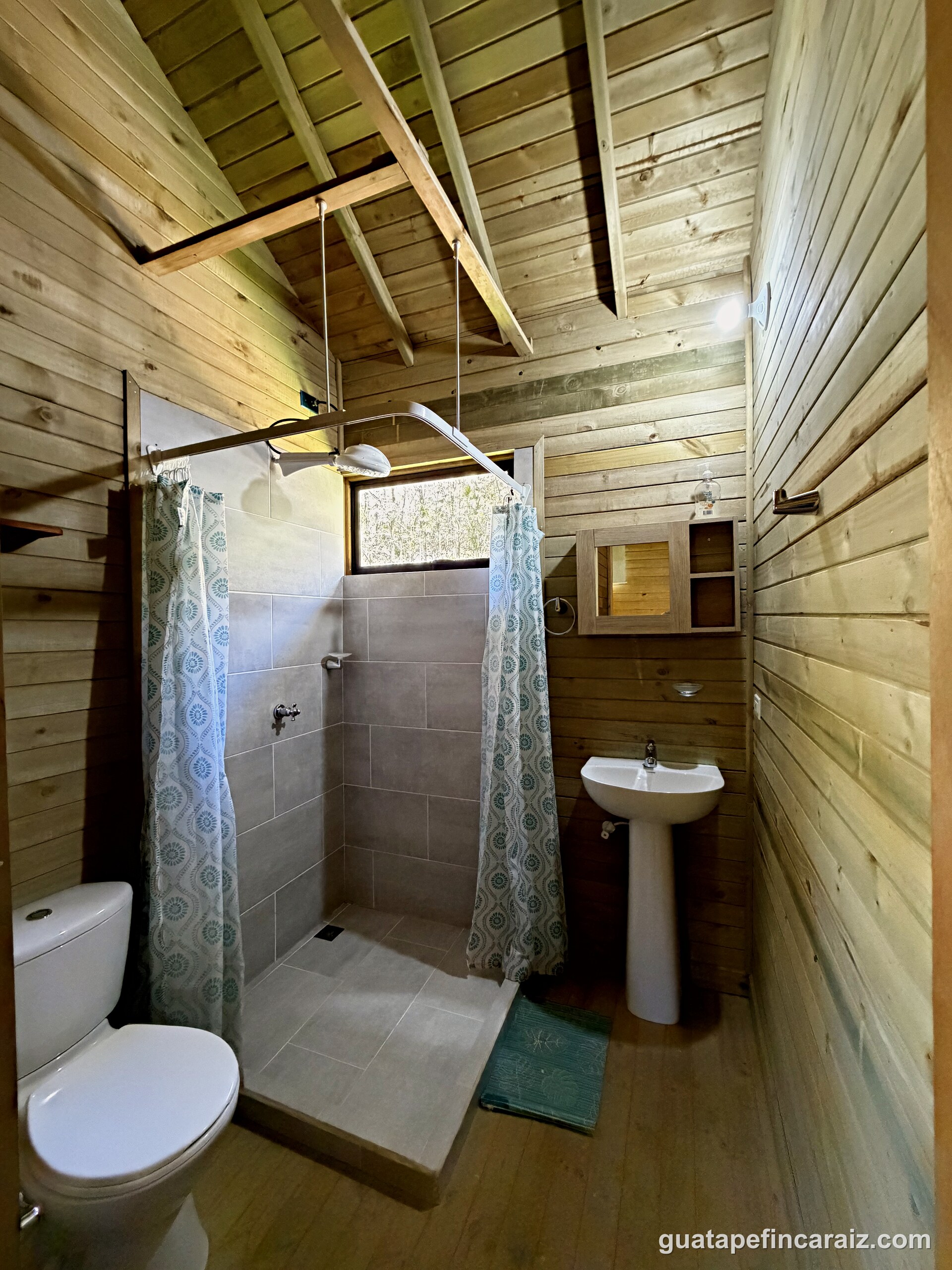 Bathroom at Cabaña del Embalse with a tiled shower, pedestal sink, and wood plank walls