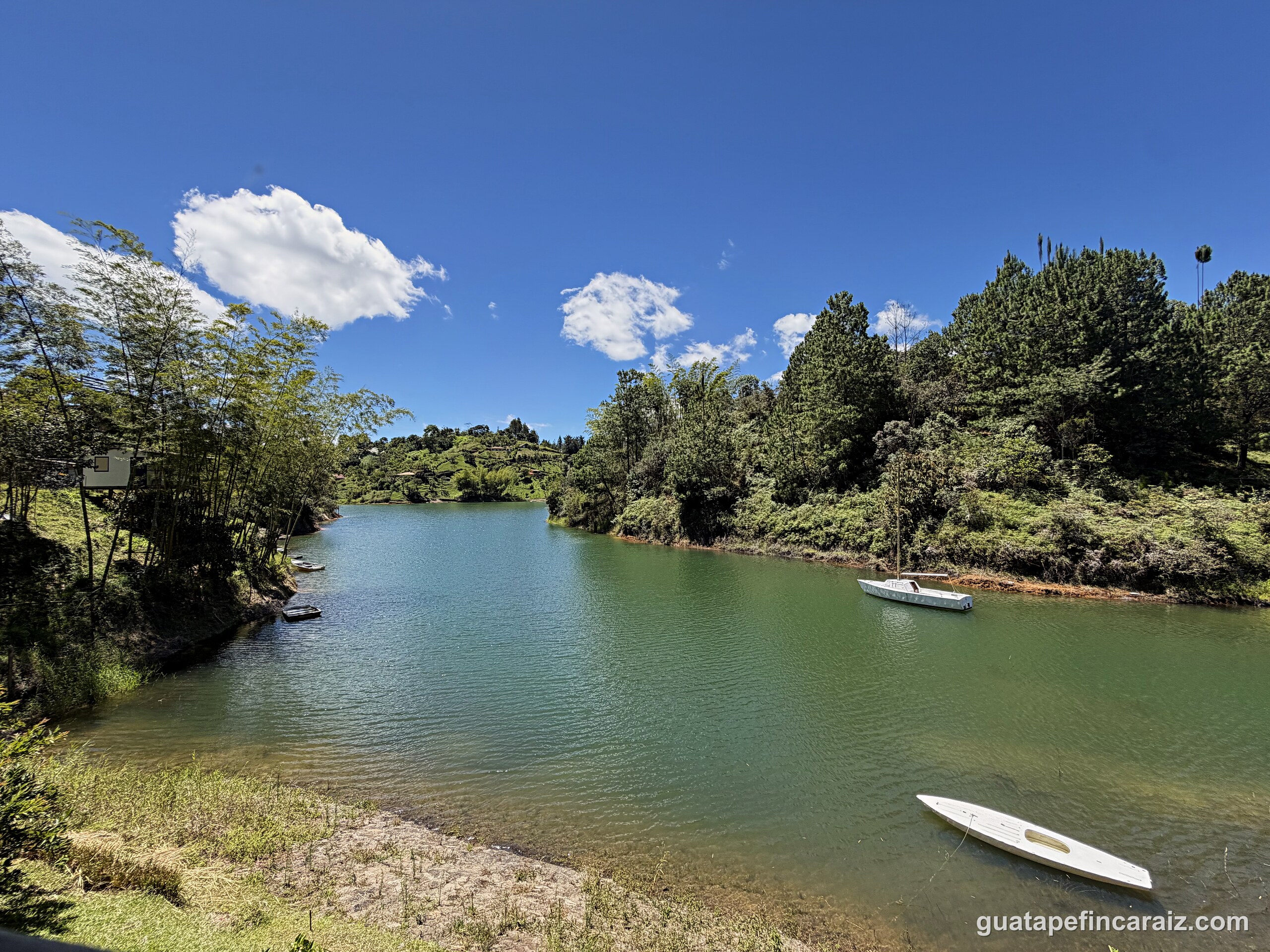 The Guatapé-El Peñol reservoir shoreline near Cabaña del Embalse with moored boats and forested banks